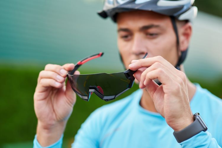 Males cyclist putting on sunglasses