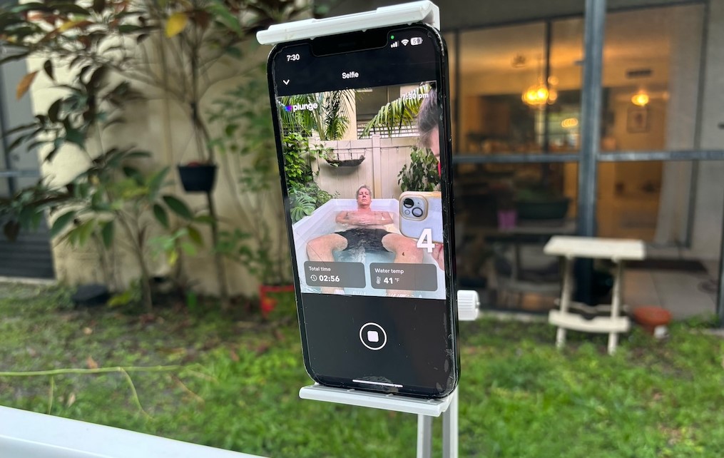 Mobile phone on a stand showing a man in an ice bath