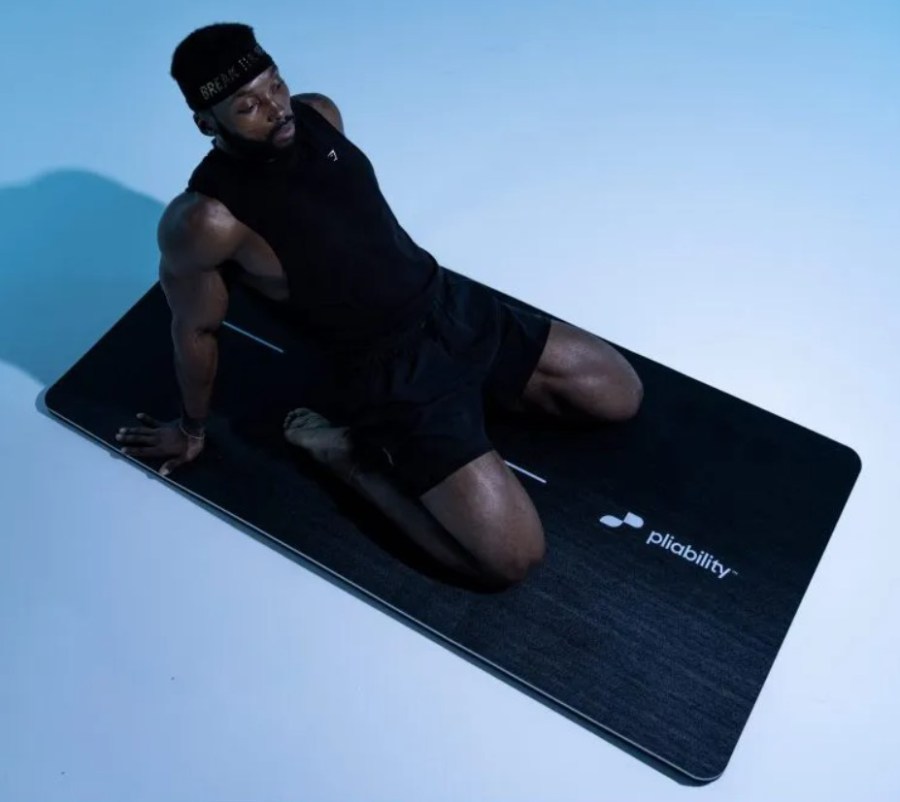 Man performing a saddle pose on an exercise mat