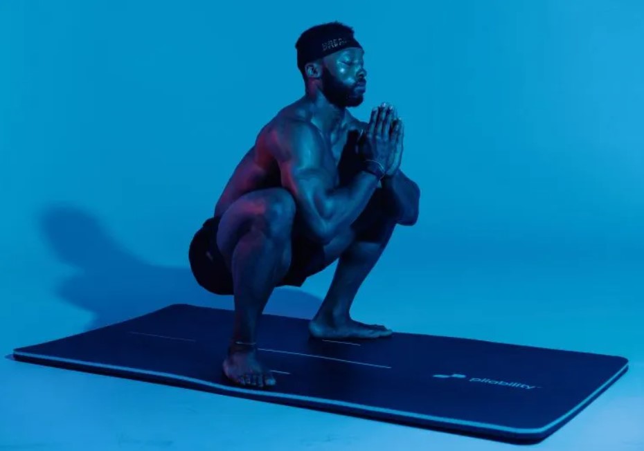 Man performing a sumo squat on an exercise mat