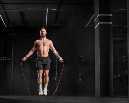 A man skipping in a gym wearing gym shorts