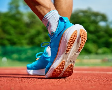 Close of a man's feet in running shoes on an outdoor track