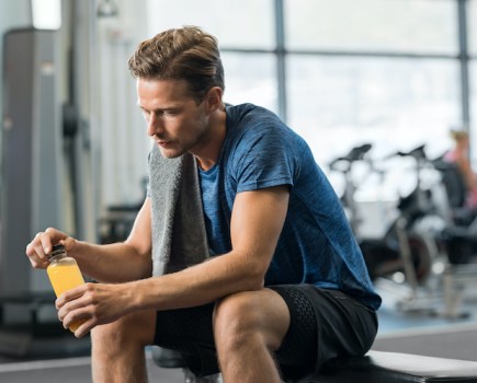 Man in a gym with a bottle of electrolyte drink