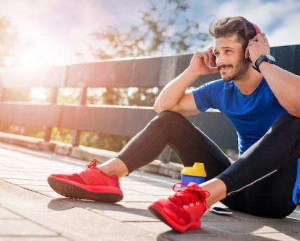 Runner sitting down putting headphones on