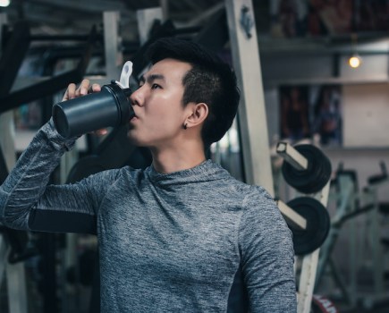 A man drinking pre-workout in a gym