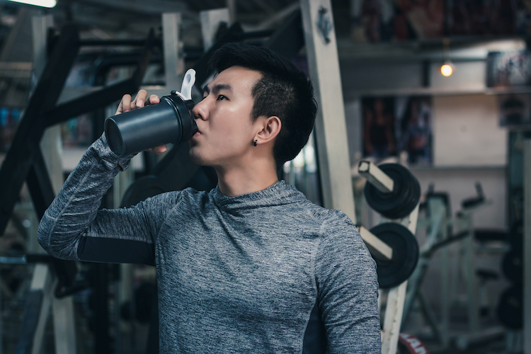 A man drinking pre-workout in a gym