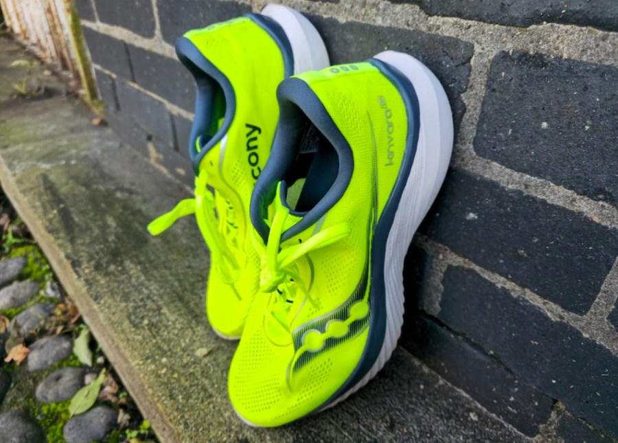 Pair of yellow running shoes propped up against a wall