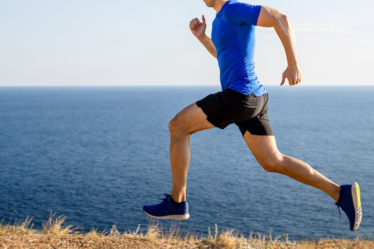 Close up of a man wearing running shorts running by the sea