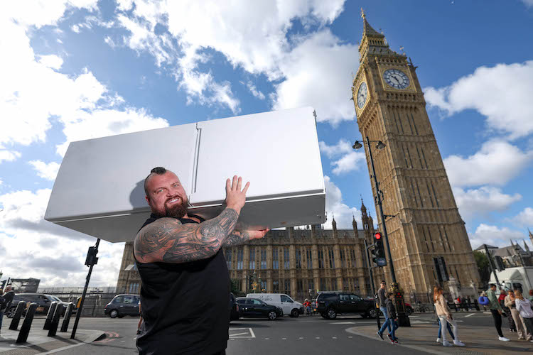 Strong man lifting a freezer outside the Houses of Parliament