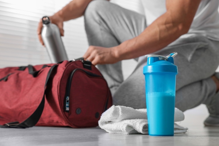 Close-up of a man putting drinks into a gym bag