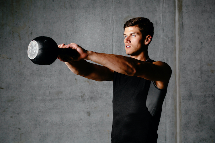 A young man swinging a kettlebell