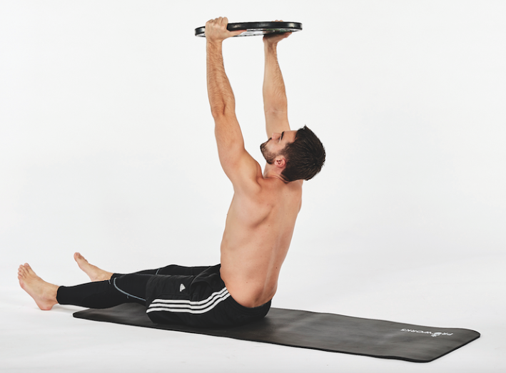 Man performing a coffin sit-up exercise with a weight plate