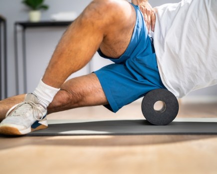 Close-up of a man's mid torso exercising with a foam roller