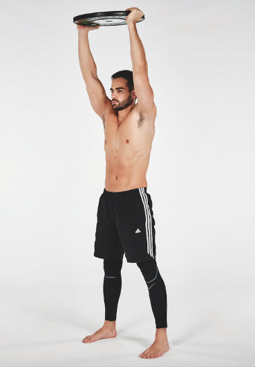 Man performing an overhead press with a weight plate