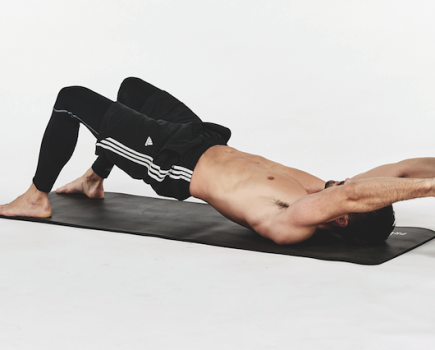 Man on a mat performing exercises with a weight plate