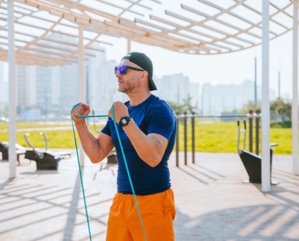 A man exercising outside with an exercise band