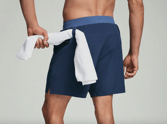 Close-up of a man with a towel looped through his gym shorts