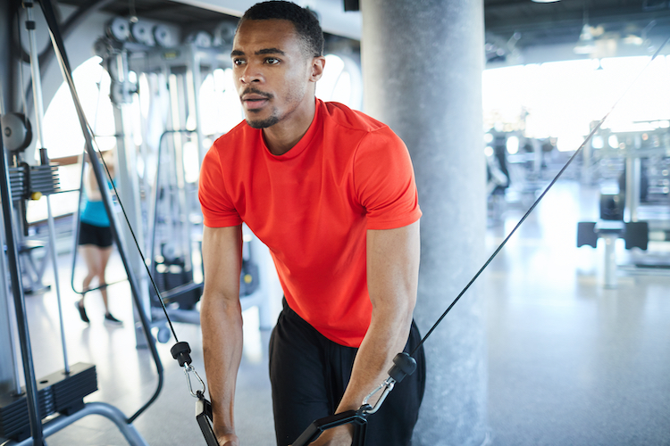 Close-up of of a man using an exercise machine in a gym