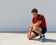 A tired male runner kneeling and recovering