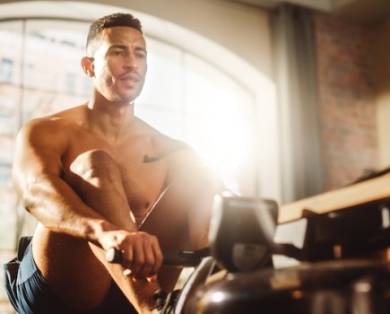 Man exercising on a rowing machine at home