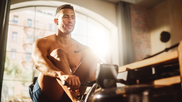 Man exercising on a rowing machine at home