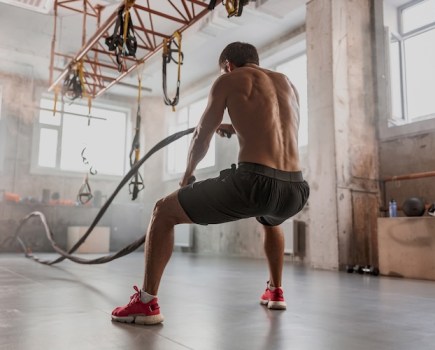 Man in a gym working out with battle ropes