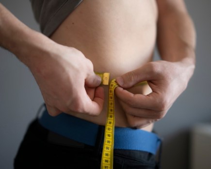 A man measuring himself round the waist