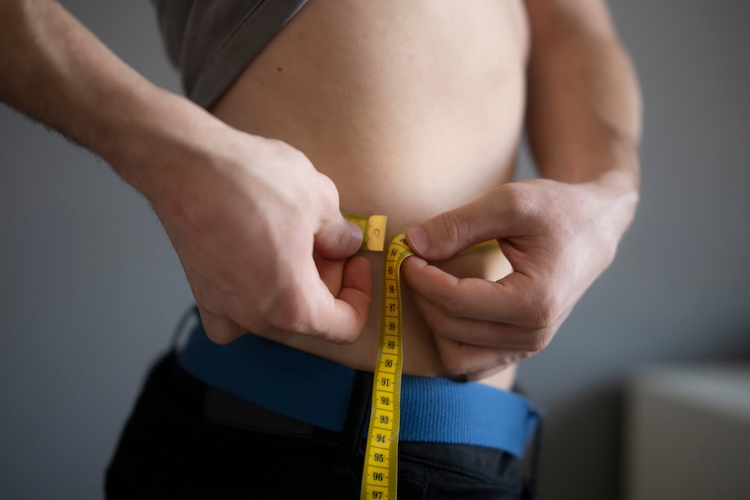 A man measuring himself round the waist