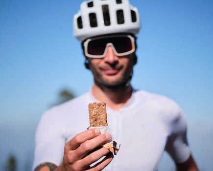 A male cyclist holding up a protein bar