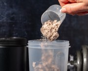 Close-up of a scoop of protein powder being poured into a beaker