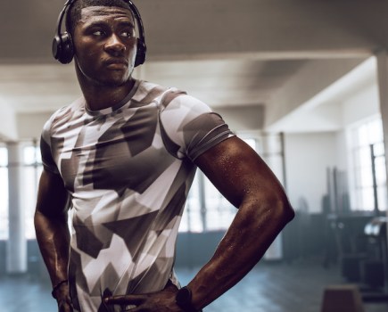 Man in a gym wearing workout headphones