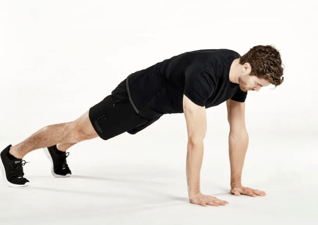 man performs an extended plank reach 