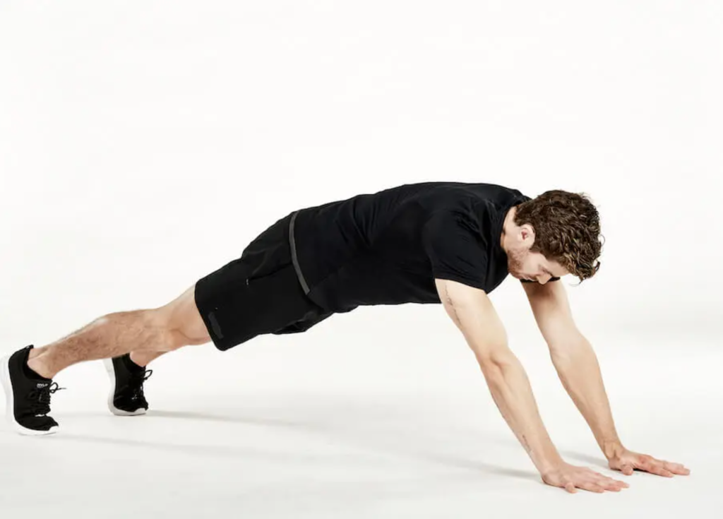 man performs an extended plank reach