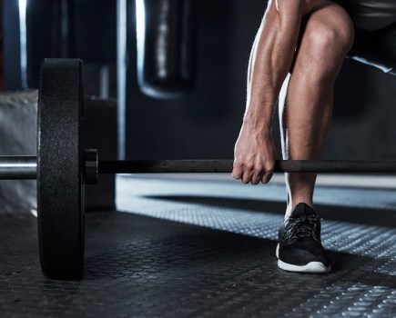 Cropped shot of a man's leg and barbell