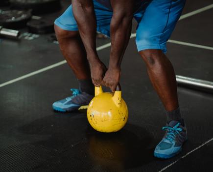 man picking up a kettlebell during a beginner's kettlebell workout