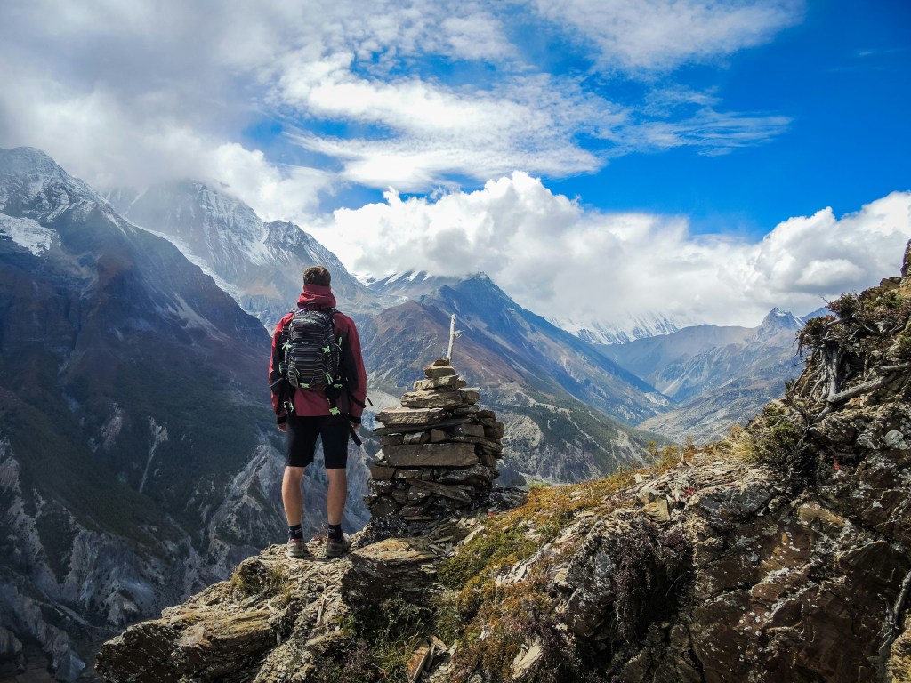 thru-hiker stands in front of a beautiful mountain