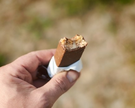 Bitten chocolate bar in a hand.