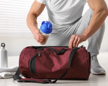 Man putting a protein shake into a gym bag