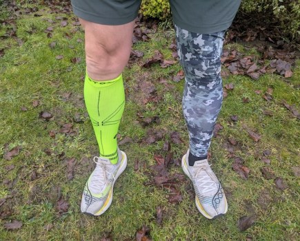 Male runner's legs wearing a compression sock on one leg and tights on the other
