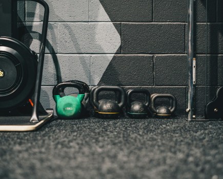 row of different kettlebells against a gym wall