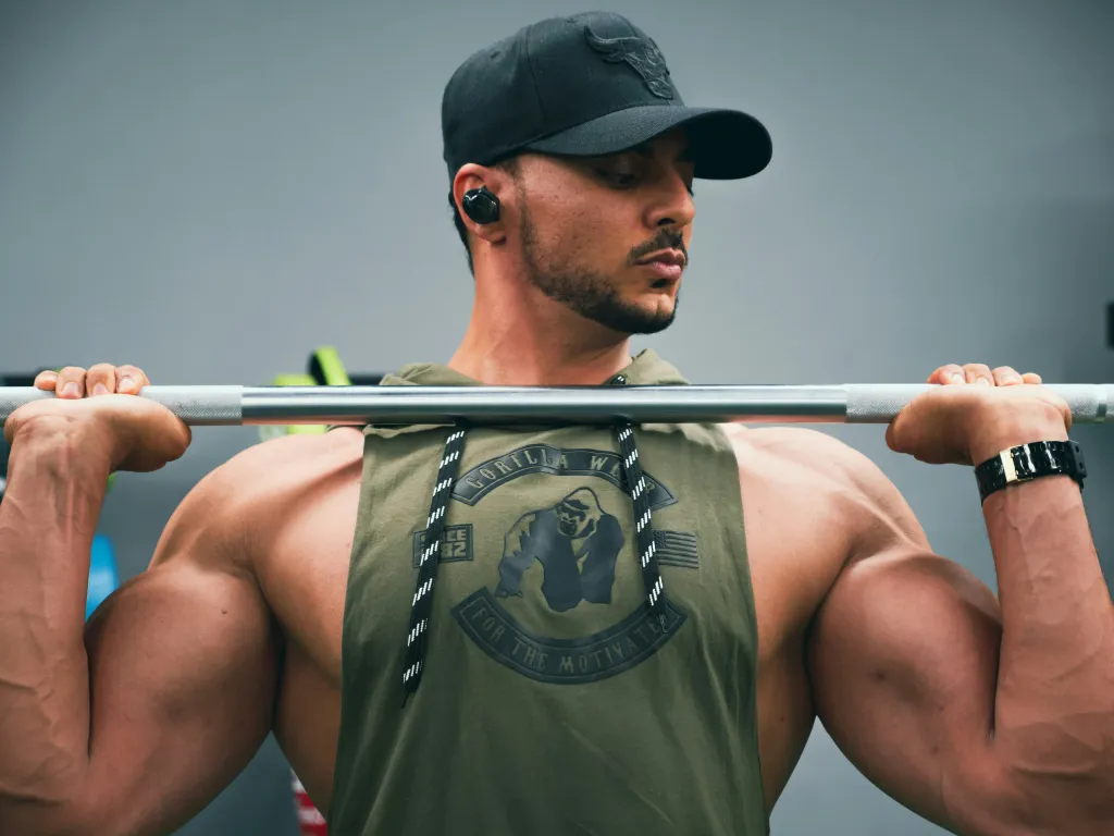 man does barbell lift while listening to music