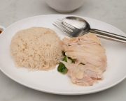 A dish with chicken, rice and cutlery on it
