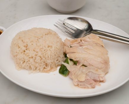 A dish with chicken, rice and cutlery on it