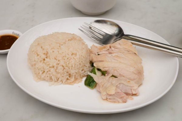 A dish with chicken, rice and cutlery on it