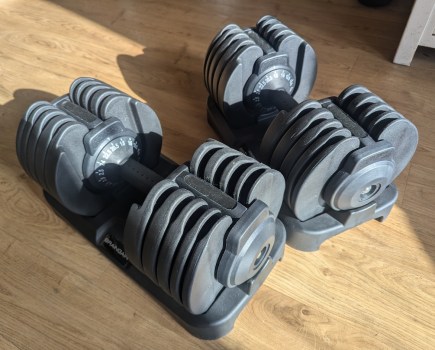 Two adjustable dumbbells on a wooden floor