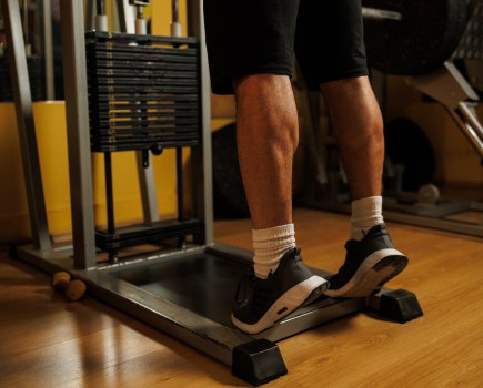 Close up view of a man is performing calf raises on the machine for calves in the gym.