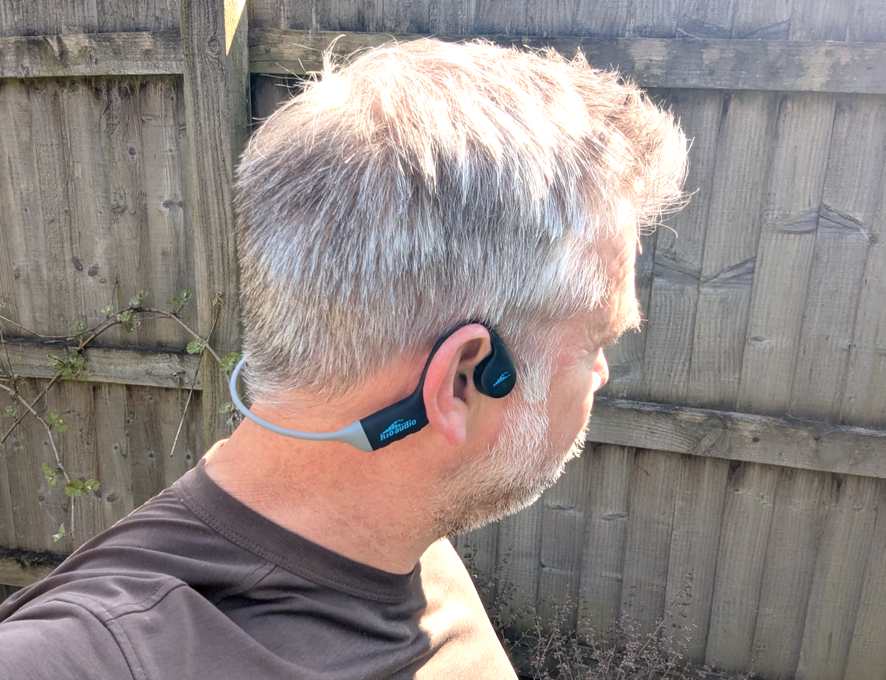 Head of a man wearing open-ear headphones