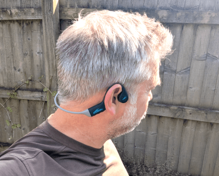 Head of a man wearing open-ear headphones