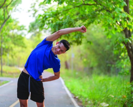 Fitness man in sport clothes stretching outdoor during warming up before training workout .