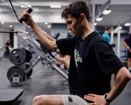 Triathlete Alex Yee performing lateral pull-downs in the gym
